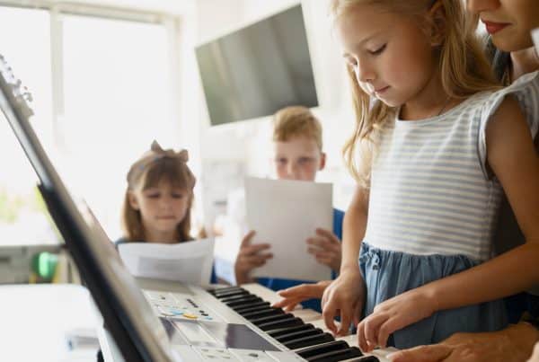 A young girl playing an electronic keyboard with her teacher.